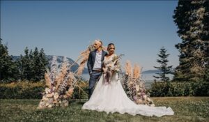 Bride and Groom pose in front of a wedding arbor.